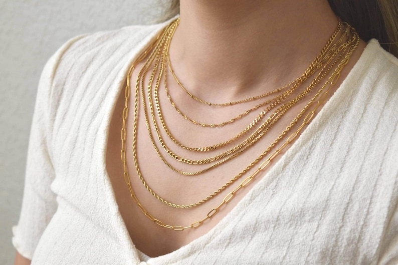 A close-up view of a woman's neck adorned with multiple gold chain necklaces.