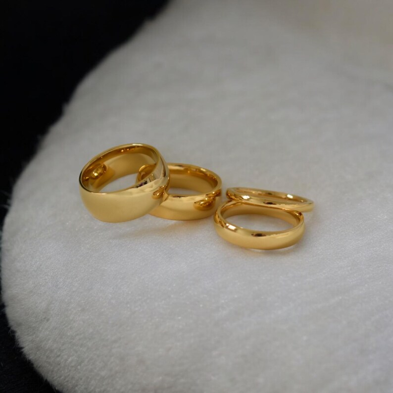 A group of gold rings is displayed on a white surface.