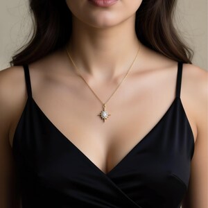 A woman wearing a black dress and a gold necklace with a pendant.