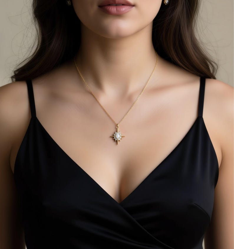 A woman wearing a black dress and a gold necklace with a pendant.