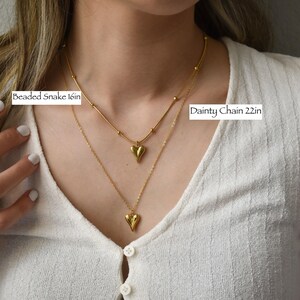 A close-up of a person's neck and chest wearing two gold necklaces, with labels indicating the size of the necklace.