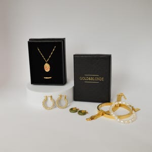 a collection of jewelry and accessories, including a necklace, earrings, and bracelets, all presented in black and gold boxes.