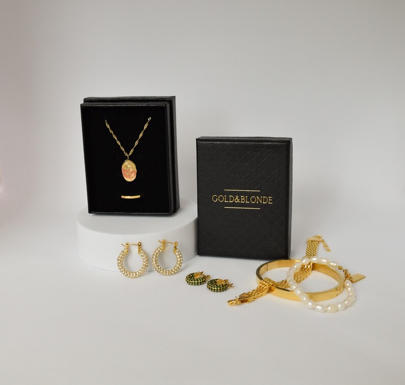 a collection of jewelry and accessories, including a necklace, earrings, and bracelets, all presented in black and gold boxes.