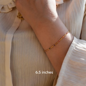 a woman wearing a gold bracelet and a white shirt