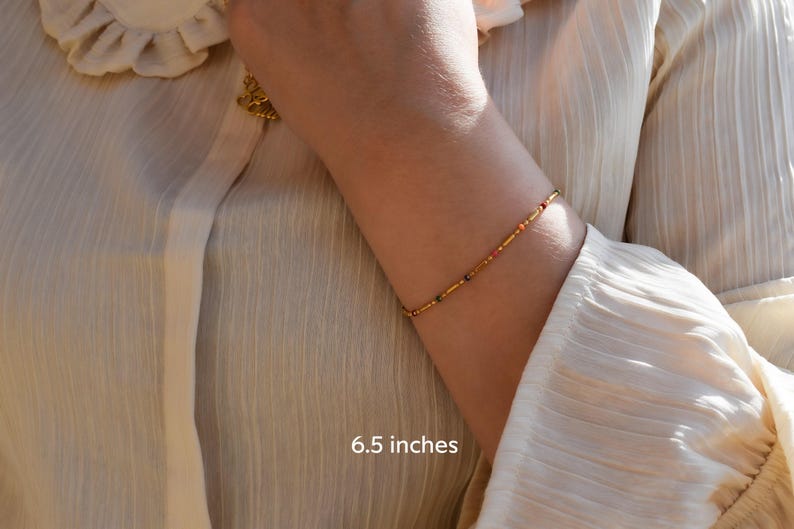 a woman wearing a gold bracelet and a white shirt