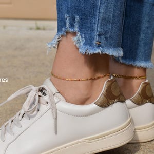 a woman wearing white sneakers with gold accents