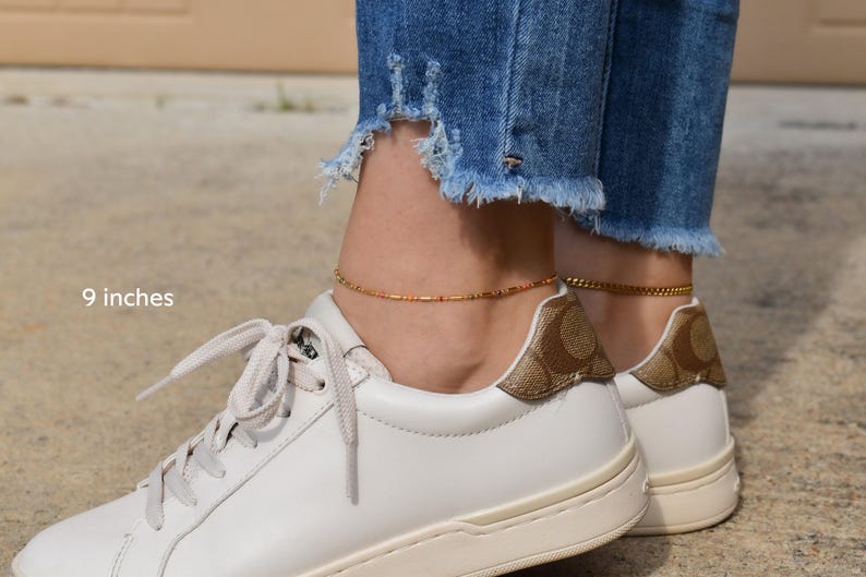 a woman wearing white sneakers with gold accents