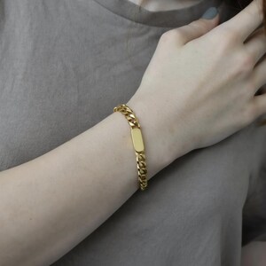 A close-up view of a person's wrist wearing a gold-colored bracelet.