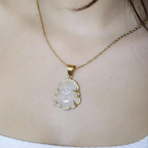 A close-up of a gold necklace with a pendant featuring a white stone or gemstone.