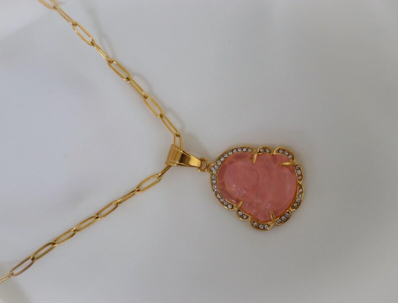 a gold necklace with a heart-shaped pendant and a red gemstone.