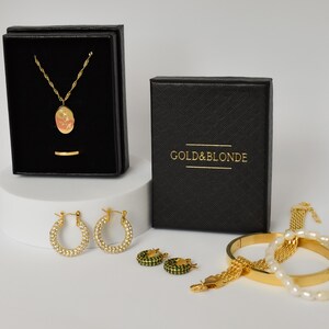 a collection of gold and silver jewelry and accessories, including a necklace, earrings, a bracelet, and a box, all presented in a black and gold color scheme.