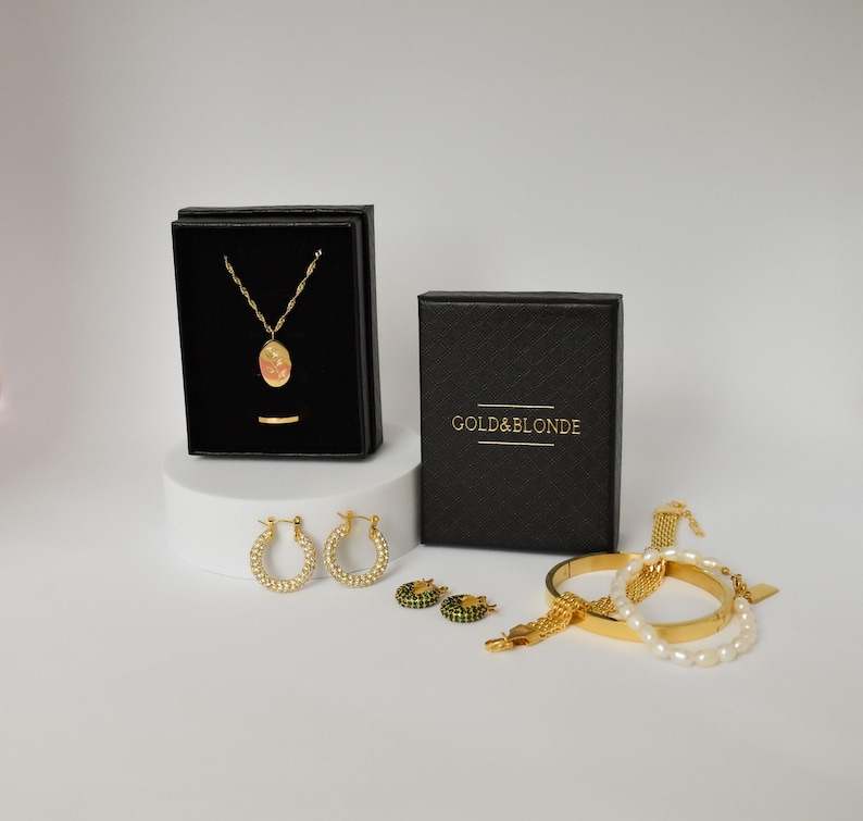 a collection of jewelry and accessories, including a necklace, earrings, and bracelets, all presented in black and gold boxes.