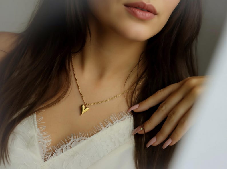 A close-up of a woman's face, focusing on her necklace and hands.