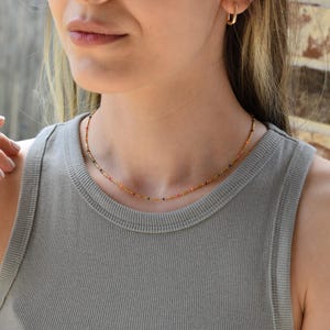 a woman wearing a gray tank top and a gold necklace