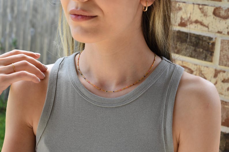 a woman wearing a gray tank top and a gold necklace