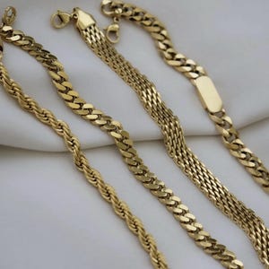 a collection of gold-colored necklaces arranged on a white surface.