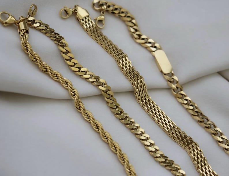 a collection of gold-colored necklaces arranged on a white surface.