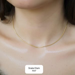 A close-up view of a woman's neck and chest area, showing a delicate gold necklace with a thin chain.