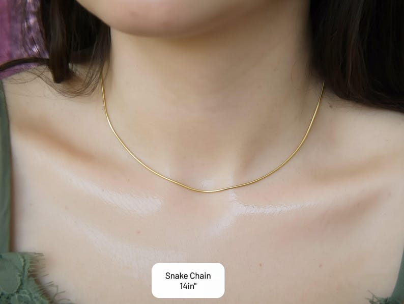 A close-up view of a woman's neck and chest area, showing a delicate gold necklace with a thin chain.