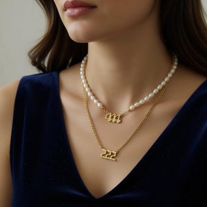 A woman wearing a gold necklace with pearls and two gold pendants with the numbers 666 and 666.