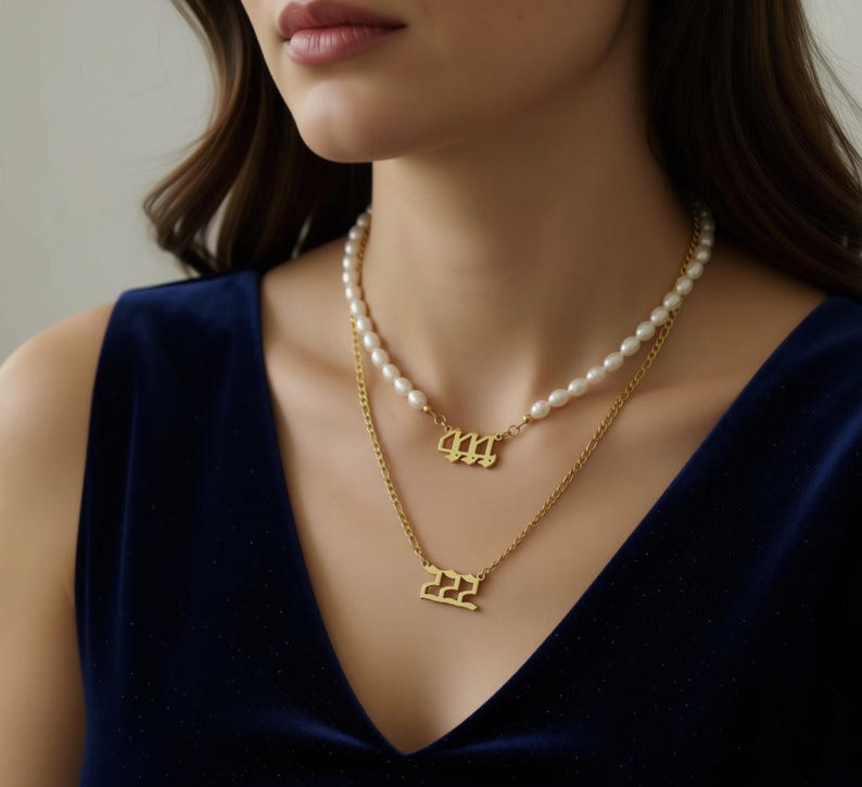 A woman wearing a gold necklace with pearls and two gold pendants with the numbers 666 and 666.