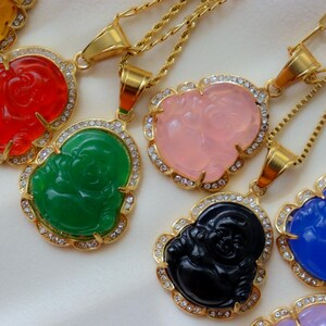 A collection of ornate gold necklaces with colorful pendants, including a green Buddha, a pink Buddha, and other vibrant designs.