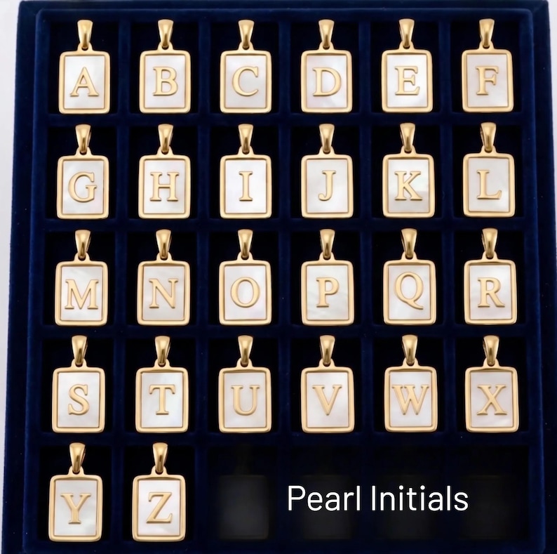 a collection of gold-colored alphabet pendants arranged in a grid-like pattern on a dark background.
