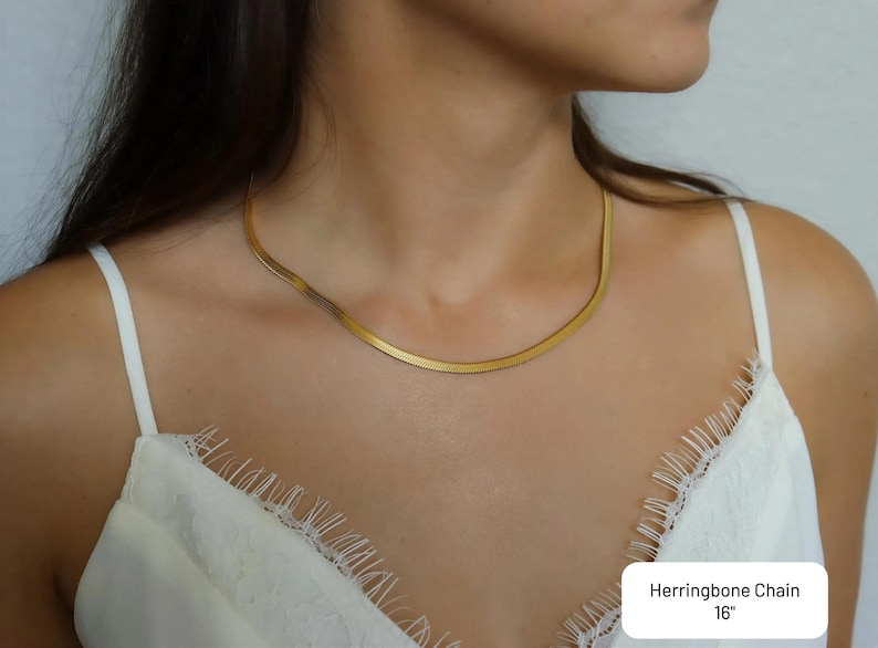 A close-up of a woman wearing a gold necklace with a thin, long chain.