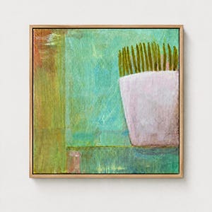 May include: A square framed painting featuring a light pink pot containing upright green grass-like blades. The background consists of layered teal, green, and earthy brown tones with visible brushstrokes, all enclosed in a natural wood frame.