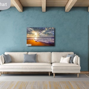 Puede incluir: Una impresi&oacute;n en lienzo de una escena de playa con una puesta de sol y olas rompiendo en la orilla. La impresi&oacute;n tiene una cita sobre encontrar la paz en medio de las tormentas. La impresi&oacute;n se muestra en una pared en un sal&oacute;n con un sof&aacute; blanco y una puerta de madera.