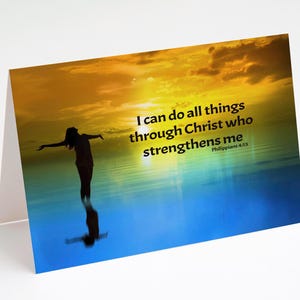 May include: A greeting card featuring a silhouette of a person with outstretched arms standing in water, with a sunset backdrop. The card includes the text "I can do all things through Christ who strengthens me" from Philippians 4:13.