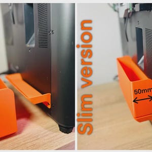 Puede incluir: Accesorio naranja versión delgada para un dispositivo negro. El accesorio es un contenedor rectangular con una anchura de 50 mm, diseñado para fijarse al lateral del dispositivo. La imagen muestra el accesorio suelto y fijado.
