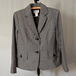 May include: A black and white houndstooth blazer with three black buttons. The blazer is hanging on a black hanger.