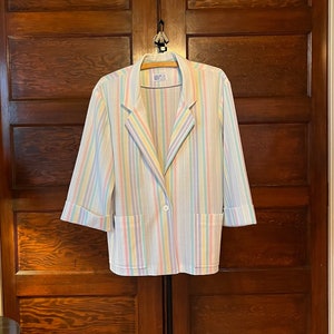 May include: A white blazer with multi-colored vertical stripes. The blazer has a single button closure and two pockets.