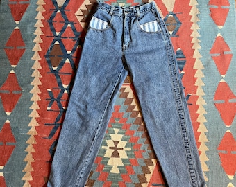 May include: High-waisted blue denim jeans with white striped pockets. The jeans have a straight leg and a relaxed fit.