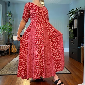 May include: A red floral print dress with a V-neck and short sleeves. The dress features a full skirt with a patchwork design of varying floral patterns. The dress is knee-length and suitable for casual wear.