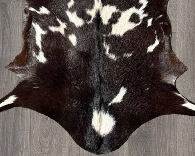 Puede incluir: Una alfombra de piel de vaca negra y blanca con un patr&oacute;n &uacute;nico. La piel es suave y flexible, y los colores son ricos y vibrantes.