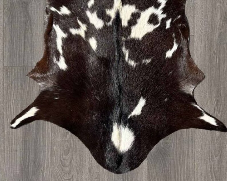 Puede incluir: Una alfombra de piel de vaca negra y blanca con un patr&oacute;n &uacute;nico. La piel es suave y flexible, y los colores son ricos y vibrantes.