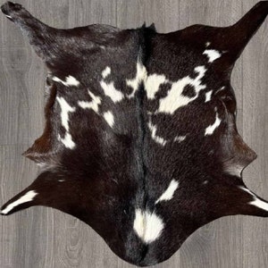 Puede incluir: Una alfombra de piel de vaca negra y blanca con un patr&oacute;n natural moteado. La alfombra es suave y esponjosa, y ser&iacute;a una gran adici&oacute;n a cualquier hogar.