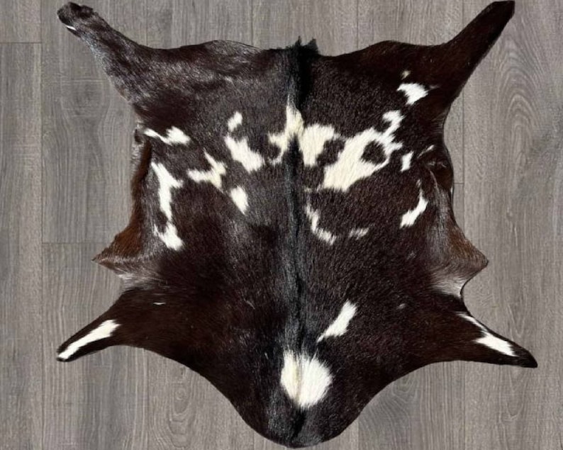 Puede incluir: Una alfombra de piel de vaca negra y blanca con un patr&oacute;n natural moteado. La alfombra es suave y esponjosa, y ser&iacute;a una gran adici&oacute;n a cualquier hogar.
