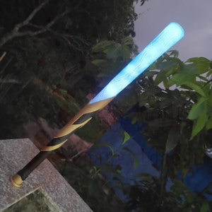 May include: A black and gold baseball bat with a blue light-up handle. The handle has a geometric pattern.