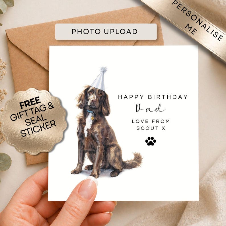 K&ouml;nnte beinhalten: Eine quadratische Geburtstagskarte mit einem braunen Hund, der einen hellblauen Partyhut tr&auml;gt. Der Text lautet: HAPPY BIRTHDAY Dad LOVE FROM SCOUT X, erg&auml;nzt durch ein schwarzes Pfotenabdruck-Symbol. Die Karte ist wei&szlig; und liegt vor einem braunen Umschlag.