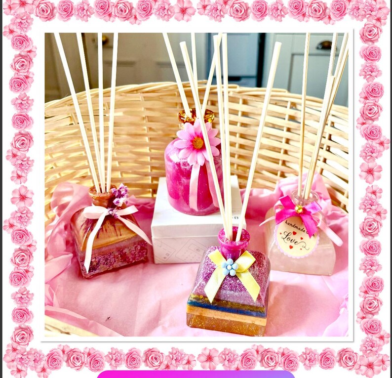 May include: Several decorative reed diffusers in shades of pink and purple. Each diffuser is decorated with ribbons, flowers, and other embellishments. The diffusers are arranged on a pink surface, with a woven basket in the background.