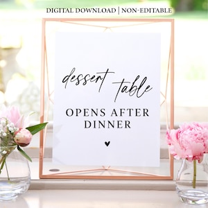 May include: A white sign with black text in a gold frame. The sign reads "dessert table opens after dinner" with a small heart at the bottom.