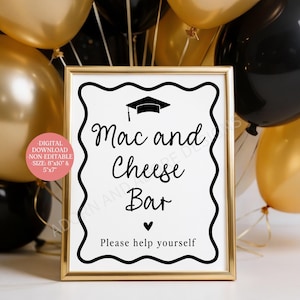 May include: A framed sign with the words "Mac and Cheese Bar" in black script, topped with a graduation cap icon. The sign is surrounded by gold and black balloons, suggesting a celebratory event. The sign also says "Please help yourself".