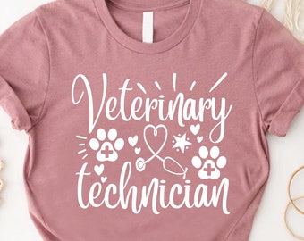 May include: A dusty rose t-shirt with the text "Veterinary Technician" in white. The text is surrounded by small white paw prints, hearts, and a stethoscope.