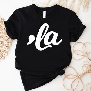 May include: Black t-shirt with a white graphic that says ",la" in a stylized font.