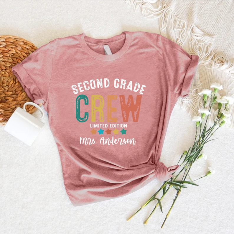 a pink t - shirt with the words second grade crew on it