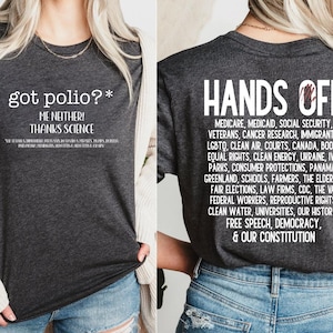 May include: Dark gray t-shirt with white text on the front that reads "got polio?* ME NEITHER! THANKS SCIENCE". The back of the shirt has the words "HANDS OFF" and a list of phrases. The shirt is made of a soft material.