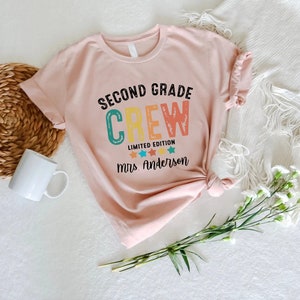 a pink t - shirt with the words second grade crew printed on it
